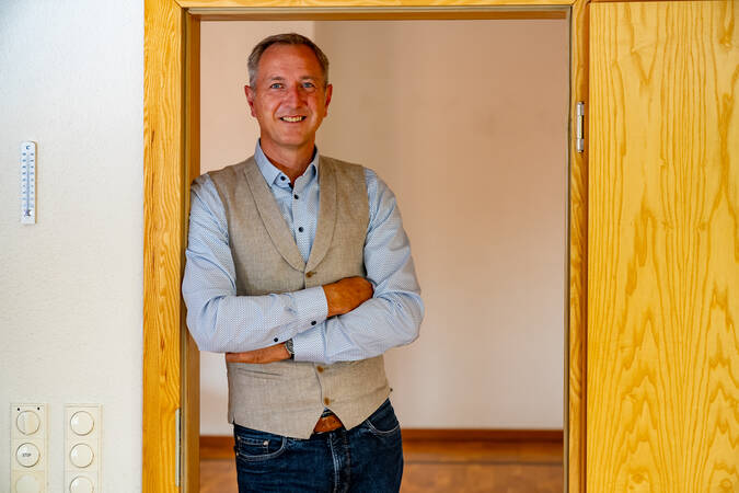 Bürgermeister Michael Schmitt steht lächelnd mit verschränkten Armen in einem Türrahmen.