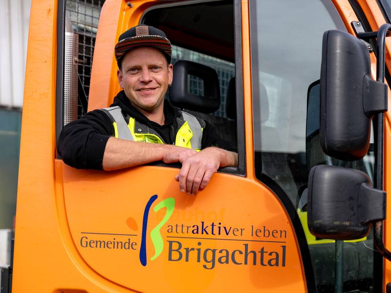 Michael Maute mit einer Schirmmütze lehnt sich lächelnd aus dem Fenster eines orangefarbenen Fahrzeugs mit der Aufschrift "Gemeinde attraktiver leben Brigachtal".
