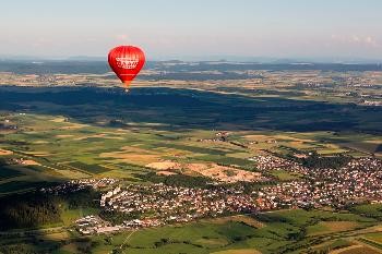 Luftbild von Brigachtal und im Vordergrund fliegt ein roter Heißluftballon