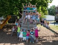 Viele Kinder stehen auf und um ein Holzspielturm
