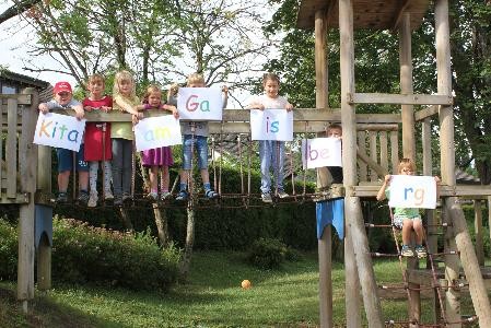 Kinder auf einem Spielturm mit Schildern mit Buchstaben drauf
